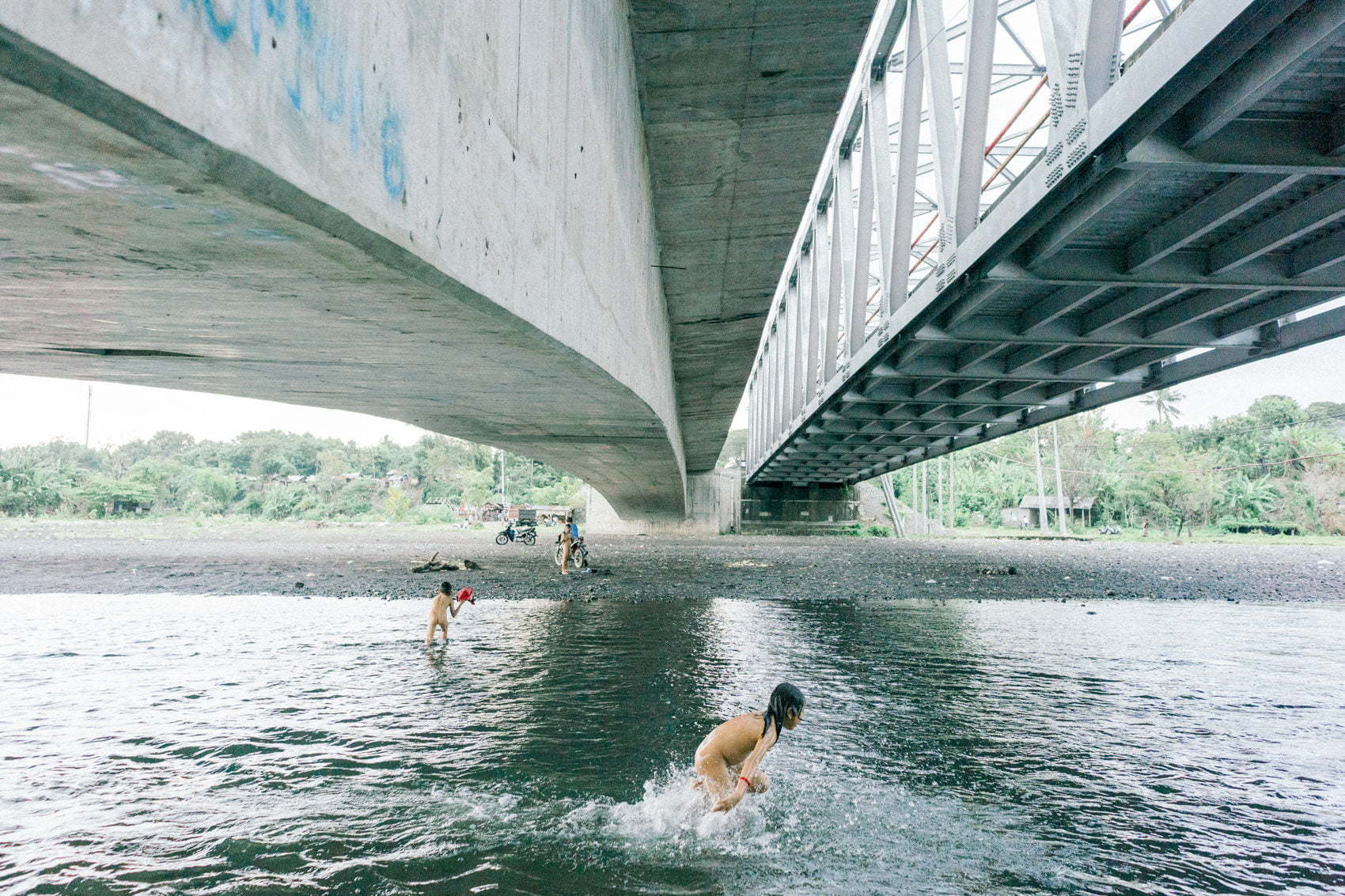 Children take a bath in the river under the bridge