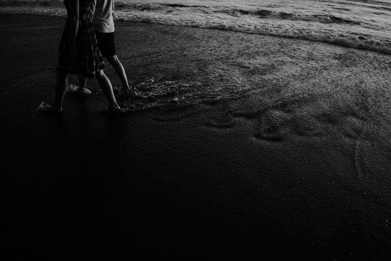 The couple walk in the shore line with the wave