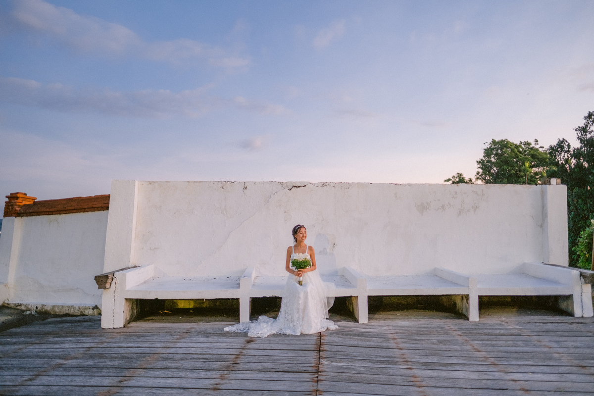 Portrait of the bride sitting down in front of the wall on a sunset